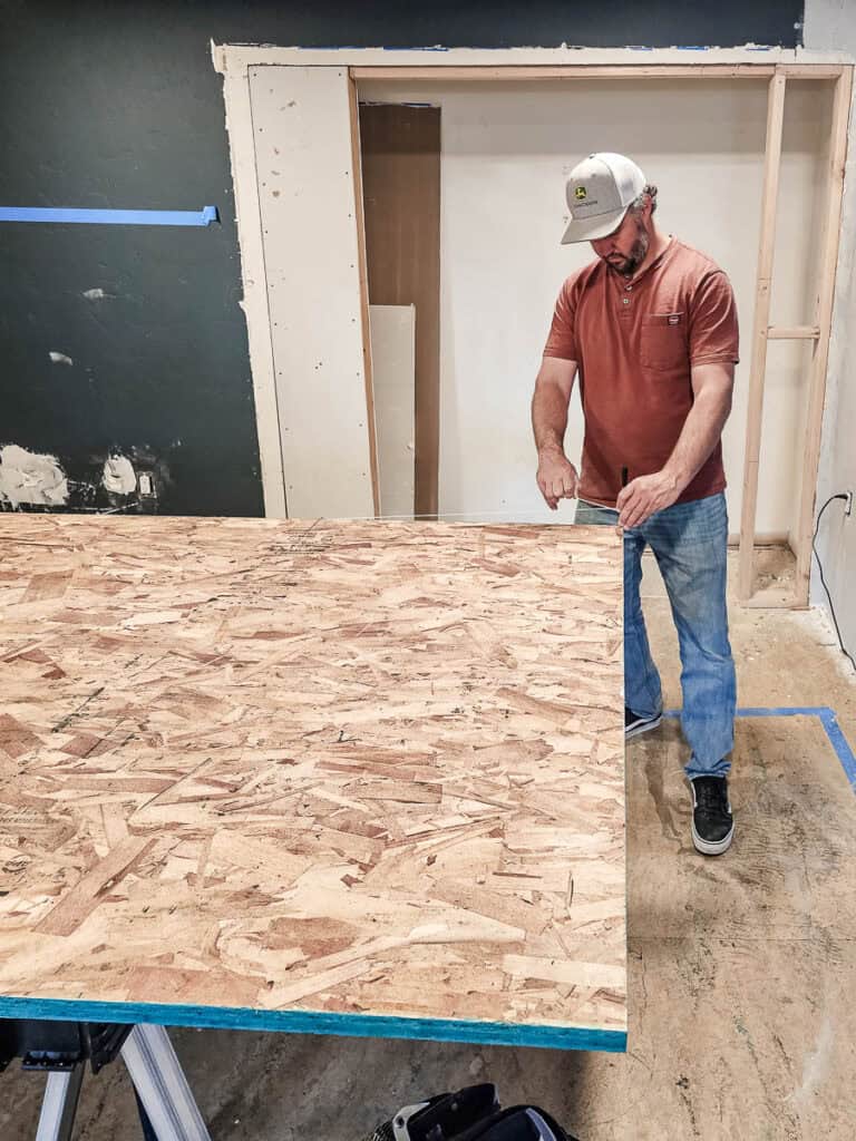 Using a string to a nail to mark an arch shape on a sheet of OSB 