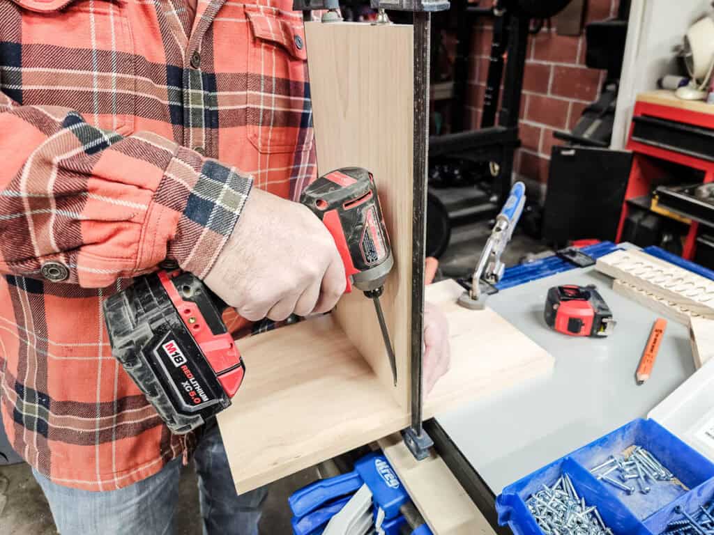 A photo of a man assembling a small bookshelf, carefully putting together the cut wooden pieces to complete the project.