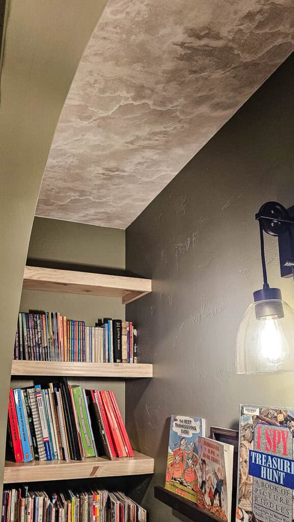 Cloud wallpaper on the ceiling in a closet with shelves full of books