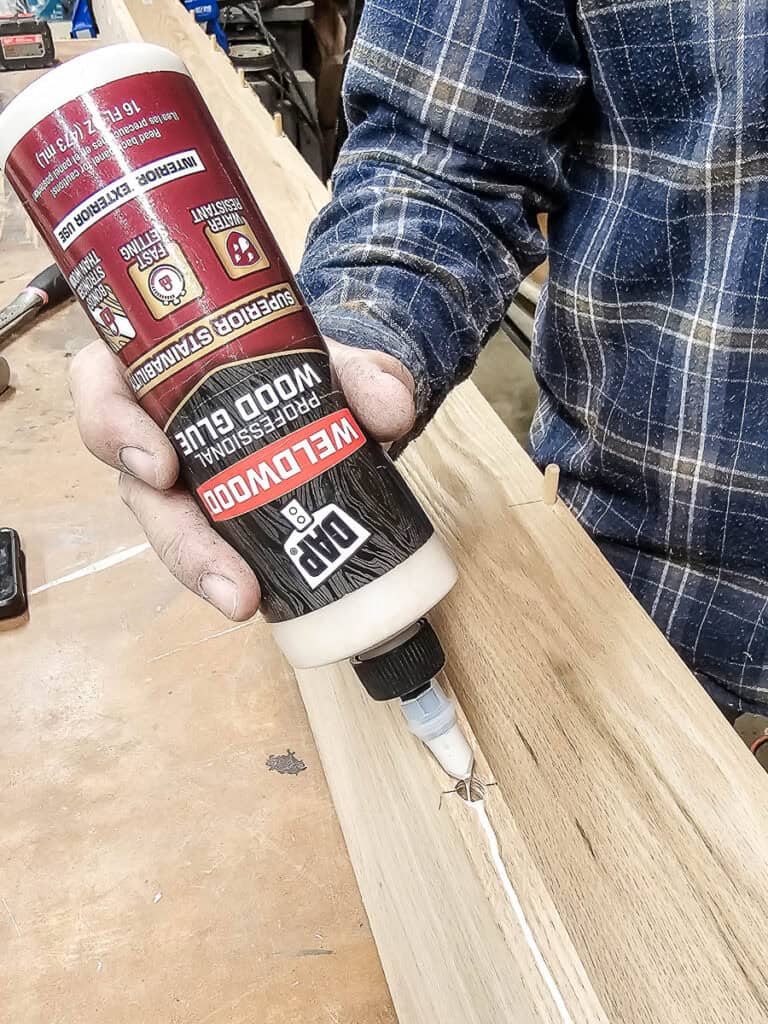Adding wood glue along joint for dowel joinery on faux wood beams made with oak wood
