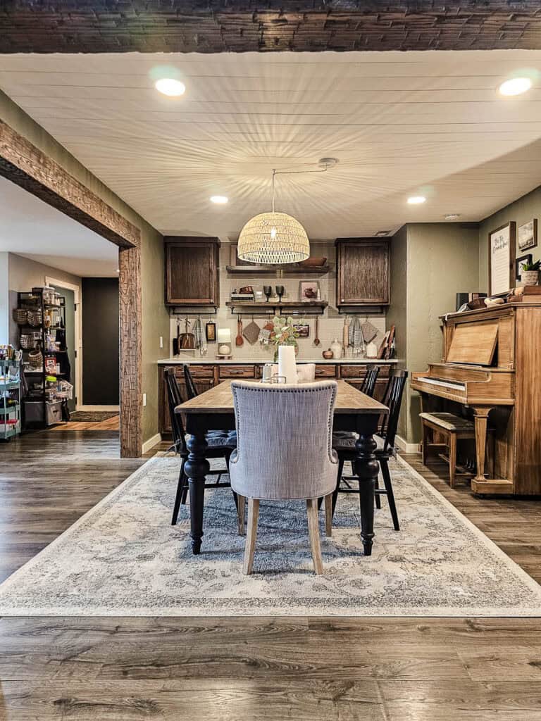 A photo of a rattan basket pendant light hanging over a rectangular table in a traditional-style dining room.