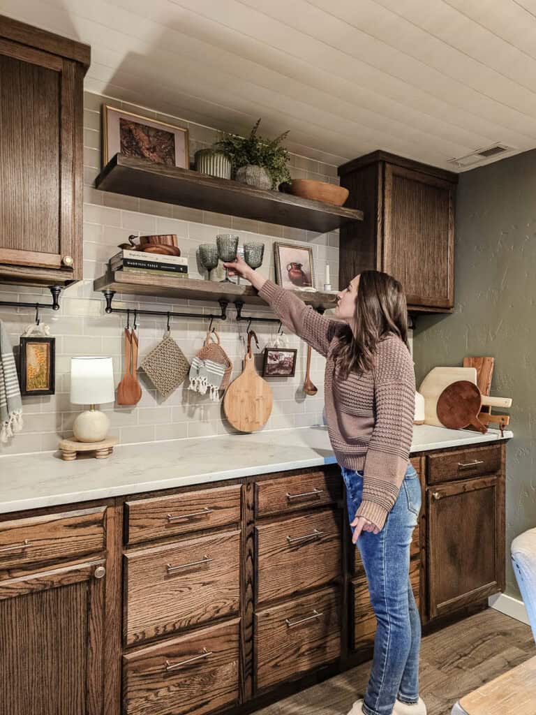 A photo of a woman with a tiled wall of built-in cabinetry and shelving in a traditional-style dining room.