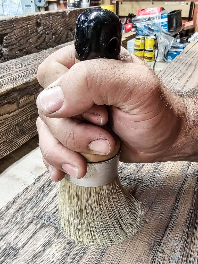 Applying wood wax on faux wood beams with a circular brush