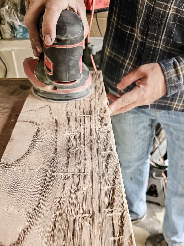 Sanding the distressed fake wood beams before finishing
