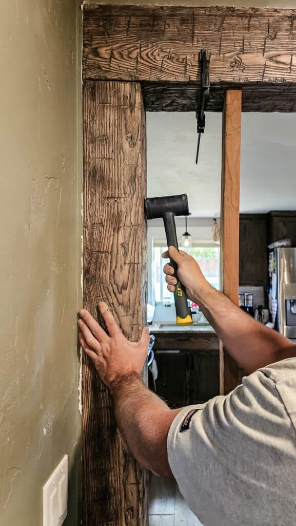 Tapping faux wood beam into place  with rubber mallet