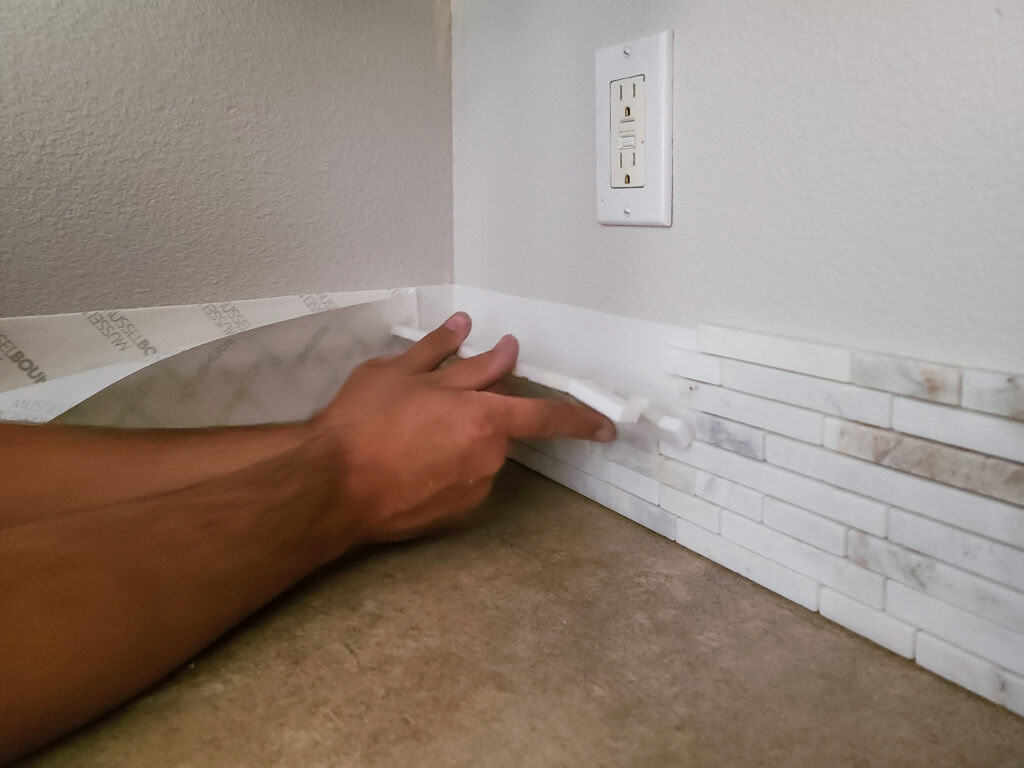 A man adding the first row of tiles.