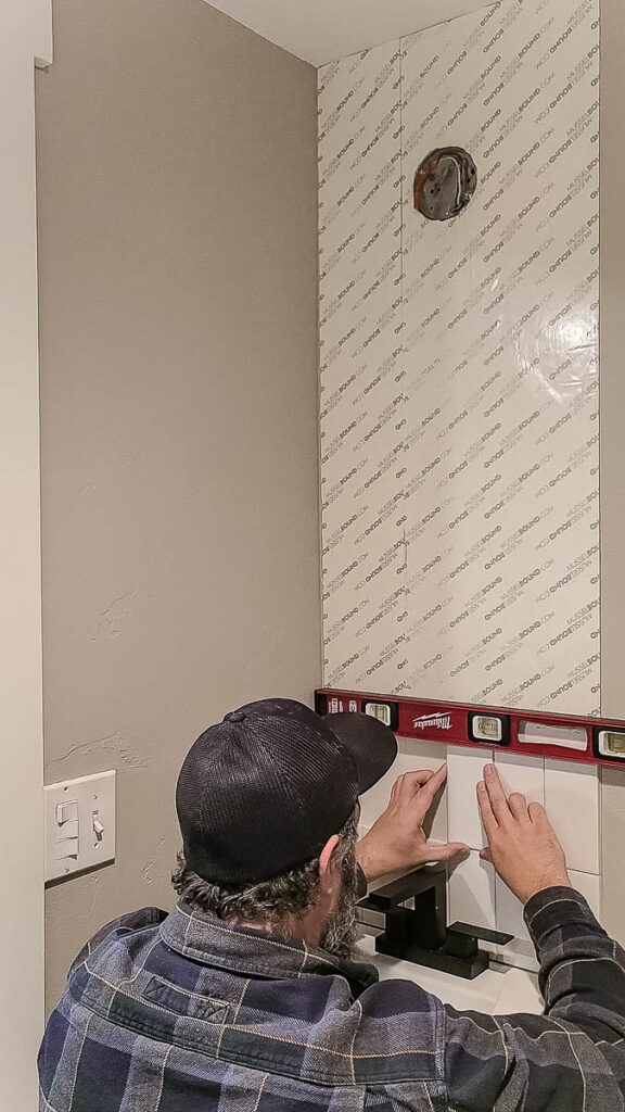 Another photo of a man applying an adhesive tile mat.