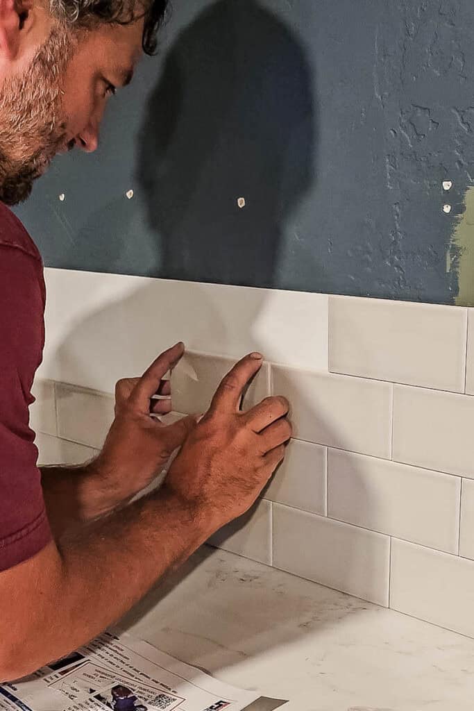 A man applying an adhesive tile mat to the wall.