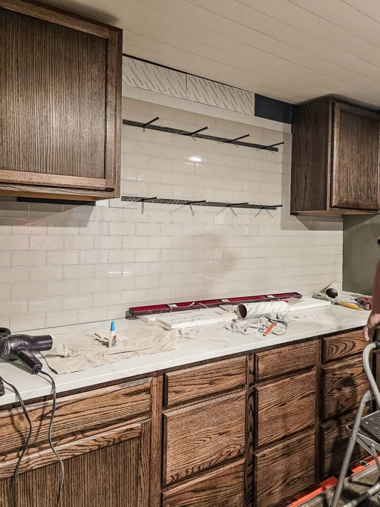 A reveal photo showcasing the completed application of the Musselbound Adhesive Tile Mat, with two cabinets on either side.