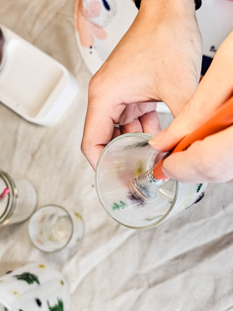 Another photo of a person carefully painting the glass with a brush.

