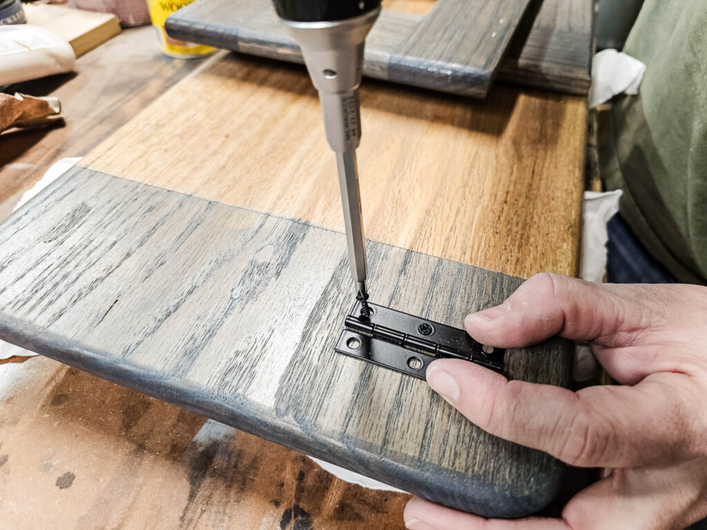 A photo of a man attaching hinges to the wooden lap desk.
