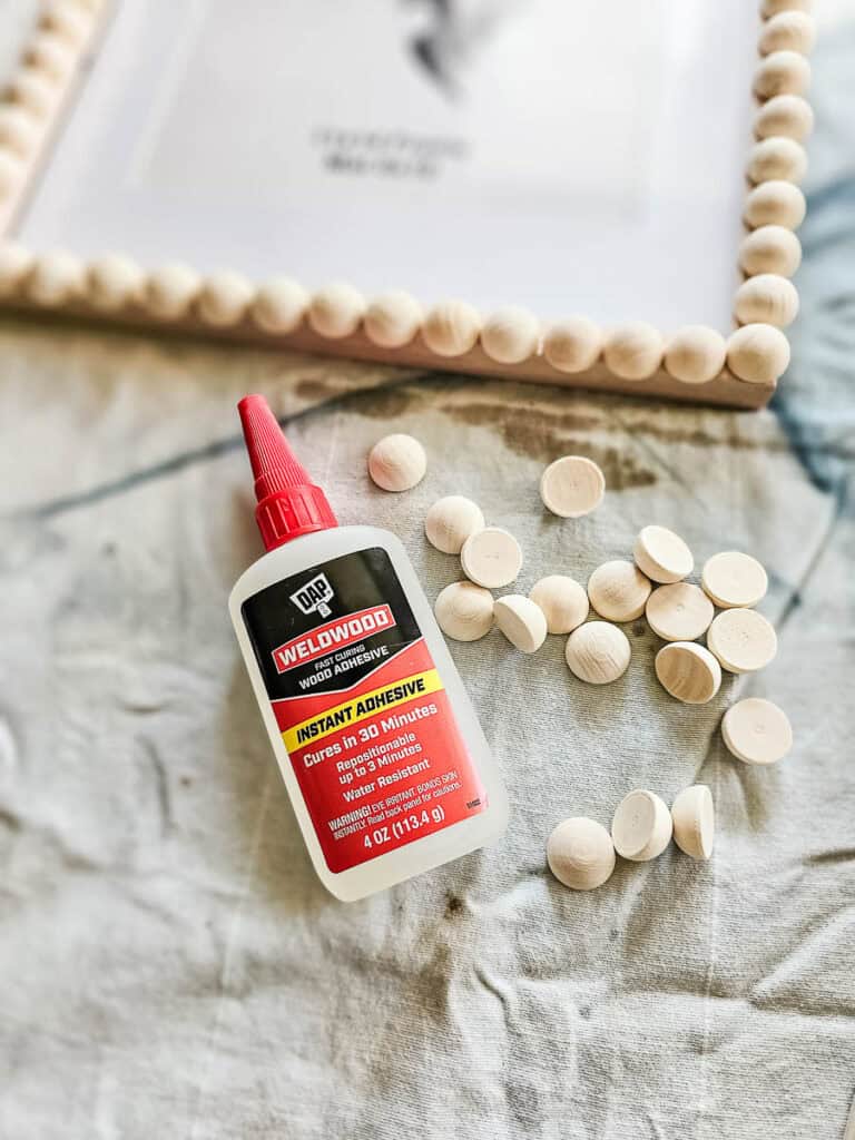 Photo of wood adhesive, wooden beads, and a wooden bead frame.