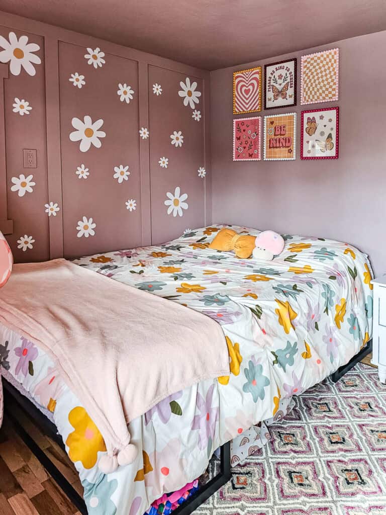 A photo of six bobbin picture frames hanging on the wall, featuring a floral design on the wall and a flower-patterned bedsheet below.
