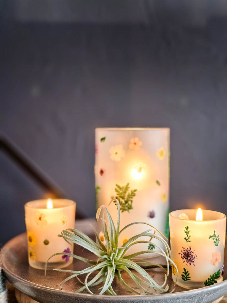 A photo showcasing three DIY pressed flower candle holders, perfect for display.
