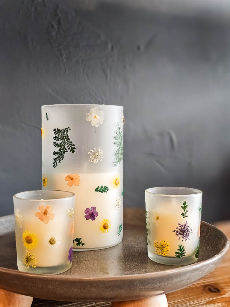 A photo displaying three glass candle holders adorned with hand-painted floral designs.
