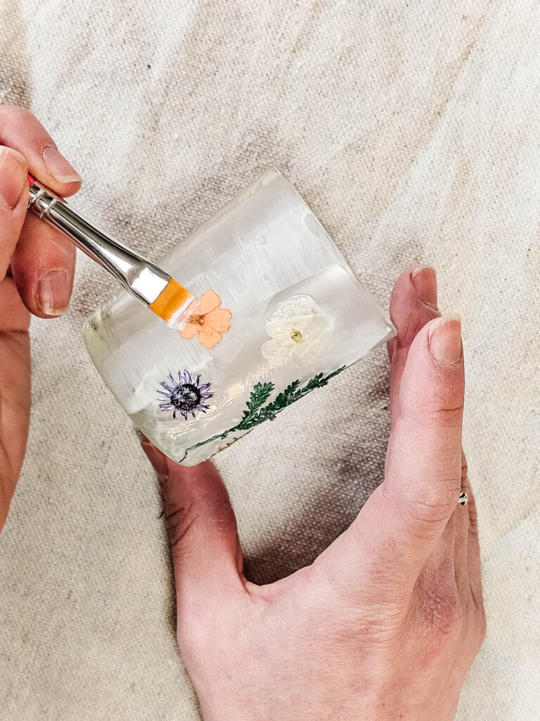 A person continuing to paint the glass using a brush.
