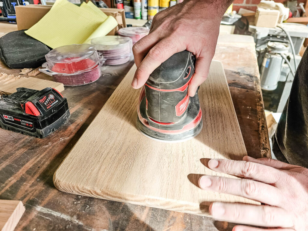 A photo of a man sanding a wooden lap desk.
