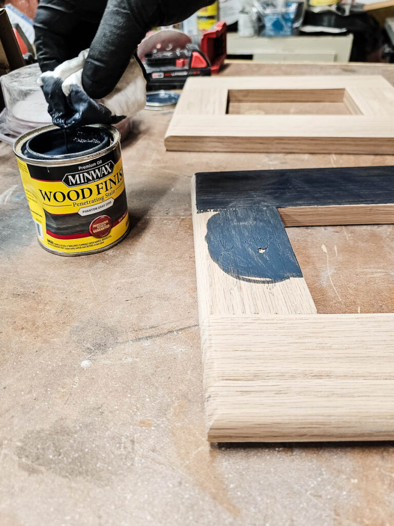 A photo of a man staining a wooden lap desk.
