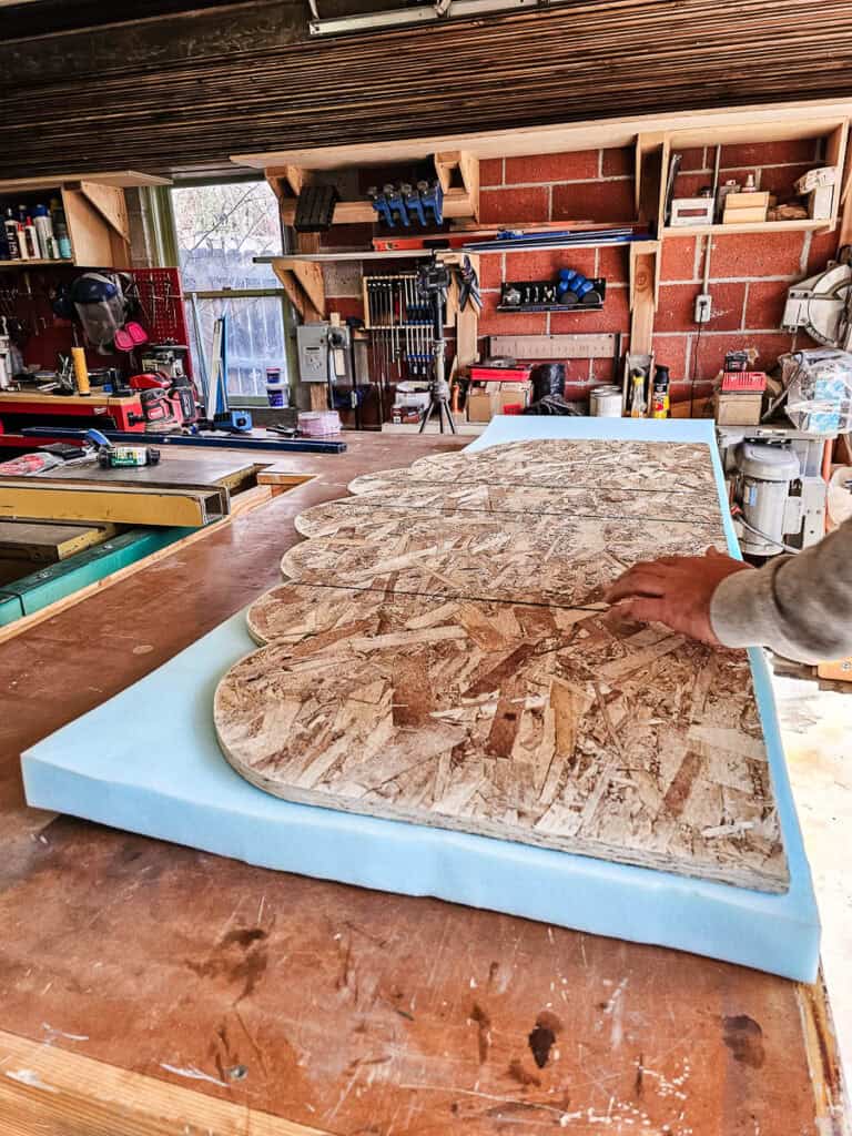 The man is keep spraying the cloud-shaped wood with glue