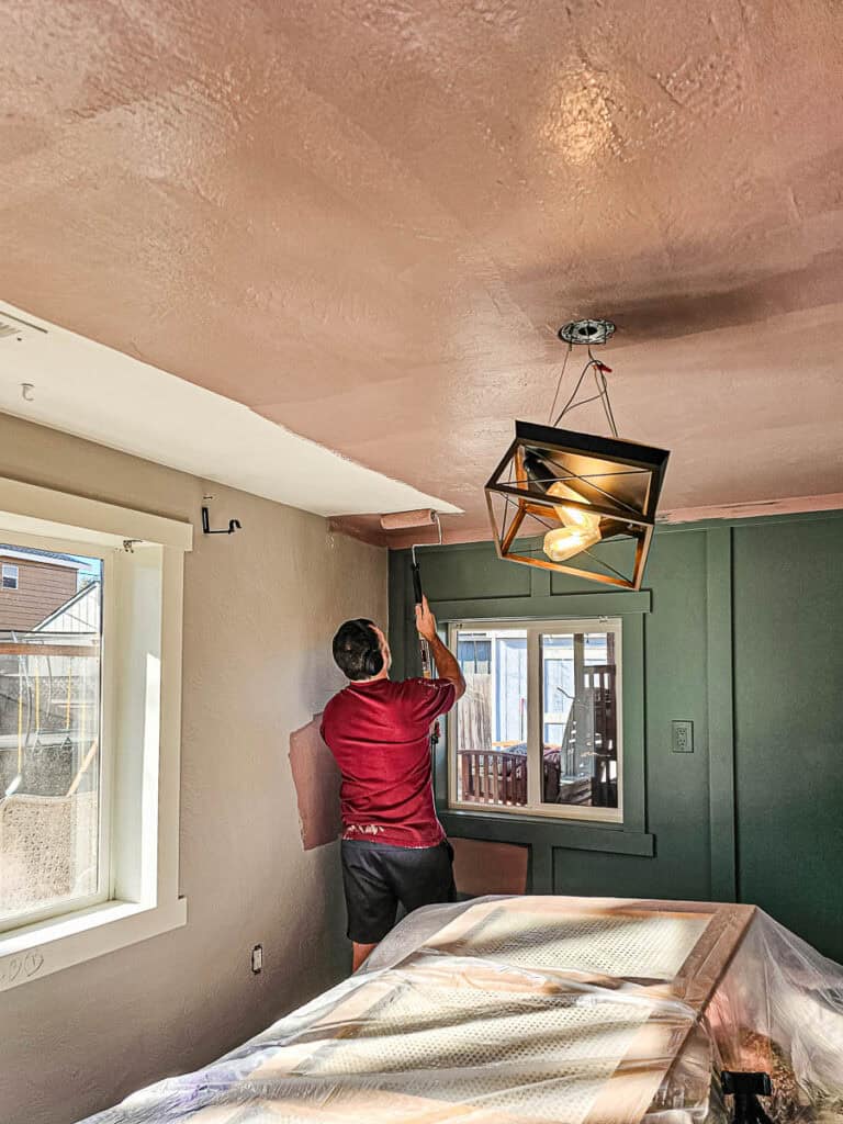 A man applying paint to the ceiling.