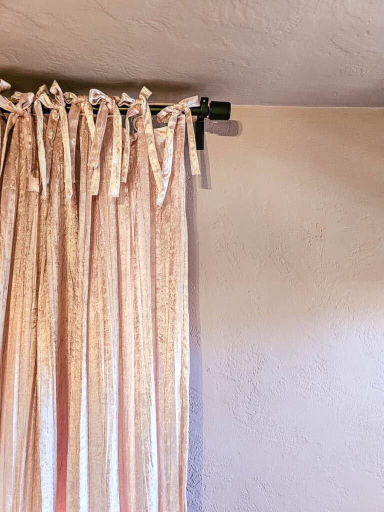 A close-up photo of a pink wall with a matching pink curtain.