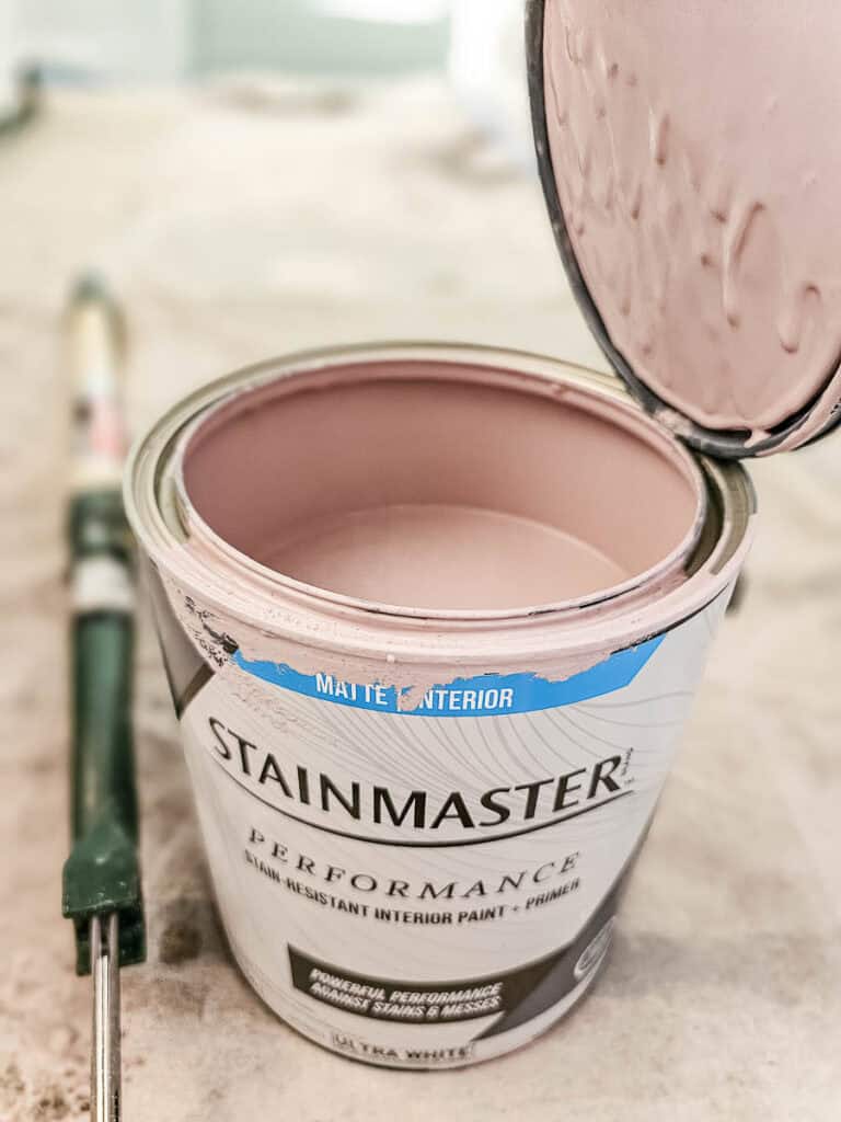 A photo of an open can of Stainmaster paint in a peach color.