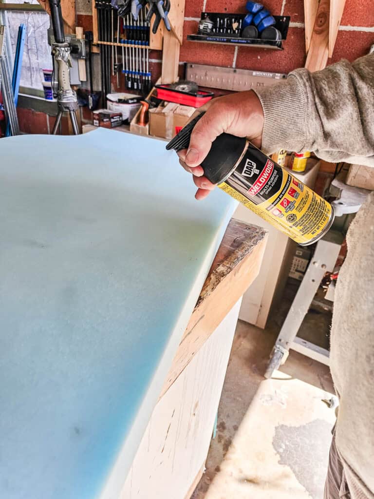 A photo of a man using DAP Weldwood Multi-Purpose Spray Adhesive on foam cushion