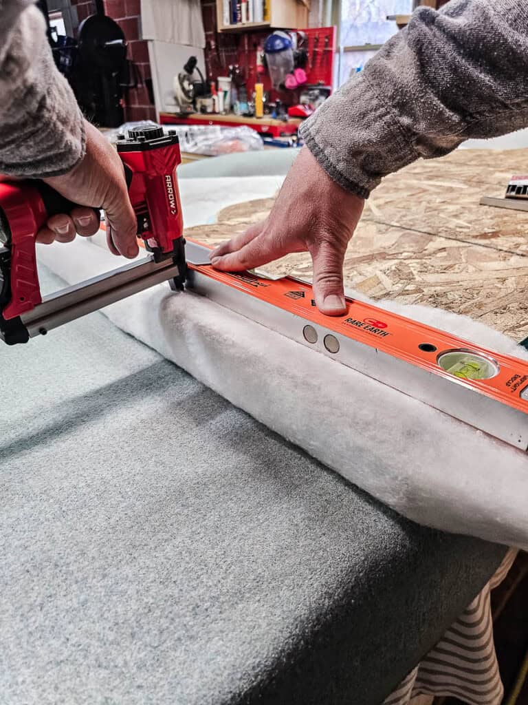 Stapling the batting onto the back of the headboard 
