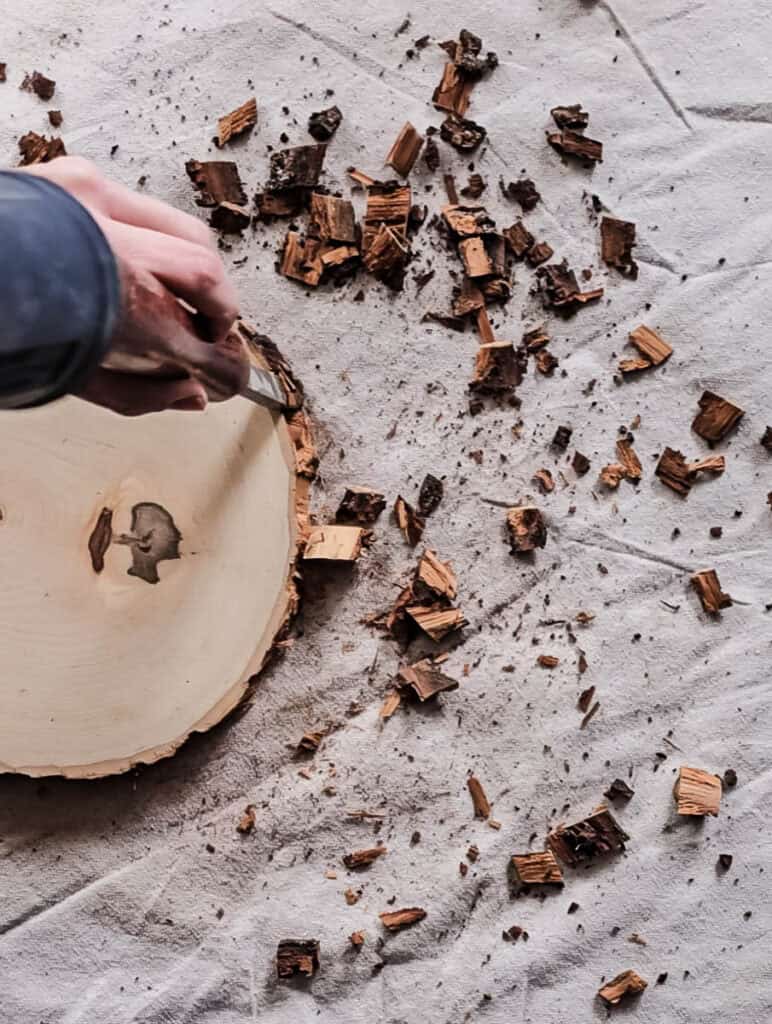 A photo of a man removing the bark from a wooden round.