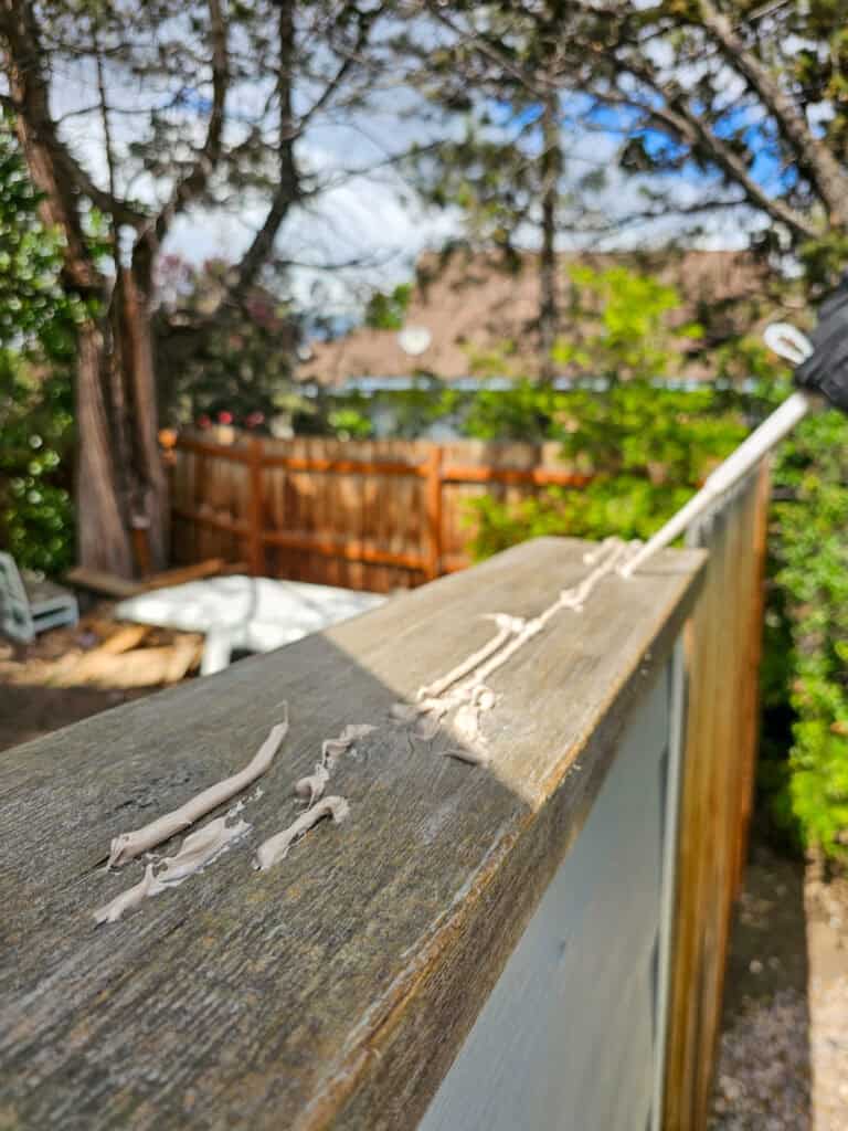 A close-up photo showing epoxy filler spread smoothly into the damaged wood surface for repair.
