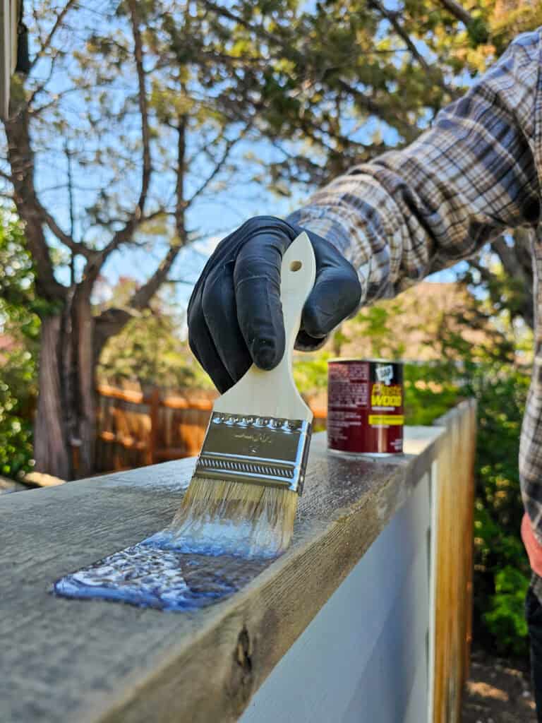 A photo of a man applying DAP Plastic Wood into the damaged section of wood for repair.
