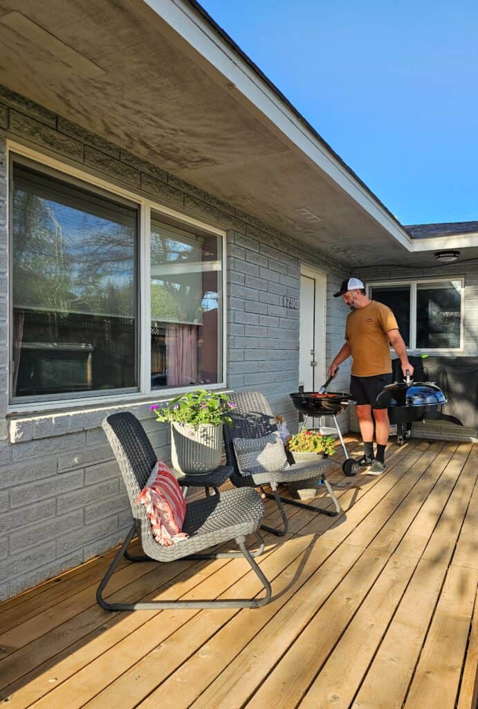 Another photo capturing backyard grilling with a man at a black charcoal grill.