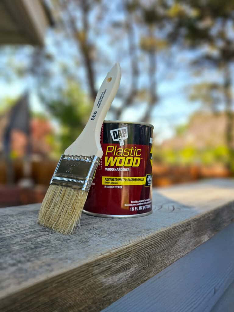 A photo showing a brush alongside an open can of DAP Plastic Wood.