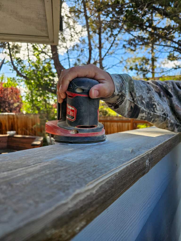Photo of a man sanding a piece of wood.