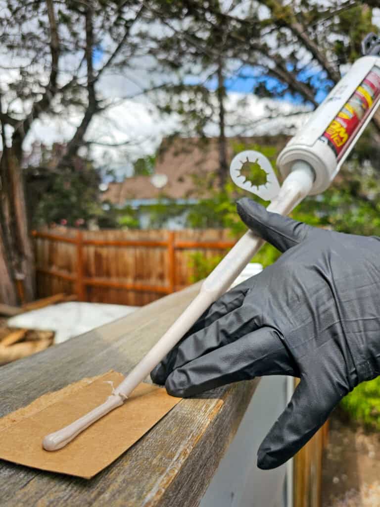A photo of a man applying epoxy filler to repair damaged wood on an exterior surface.
