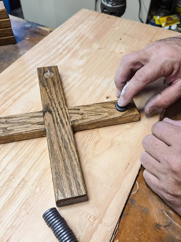 A man attaching a magnet into the drilled hole in the wood.