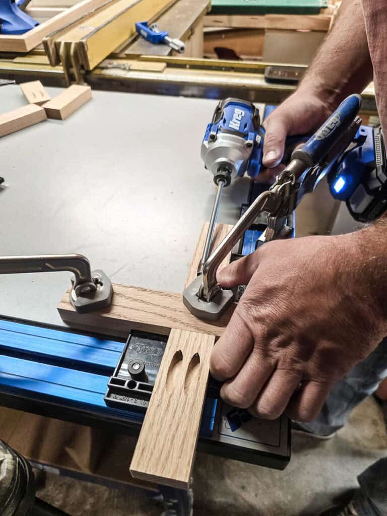 A man drilling precise pocket holes to create the wooden X pieces for the DIY Tic Tac Toe board.