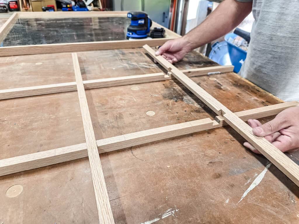 A man marking and routing groove locations for the Tic Tac Toe board so they fit together like a puzzle