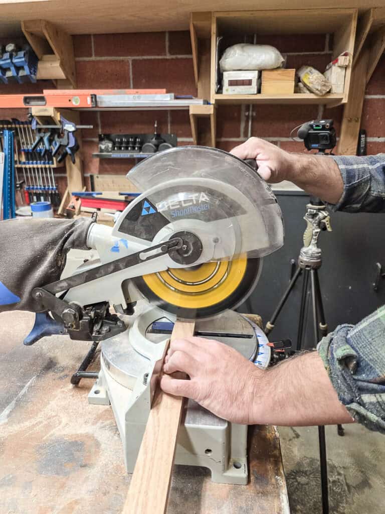 Another photo showing a man cutting wood with a circular saw to create a Tic Tac Toe board.