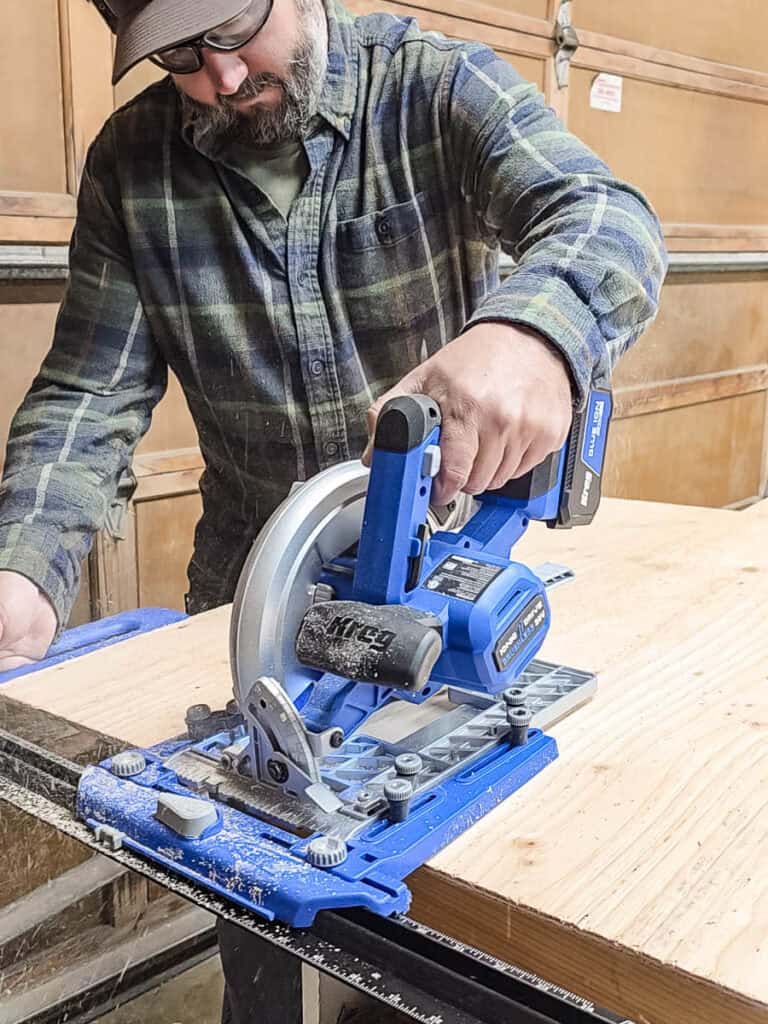 A man cutting wood with a circular saw to make a DIY Tic Tac Toe board.