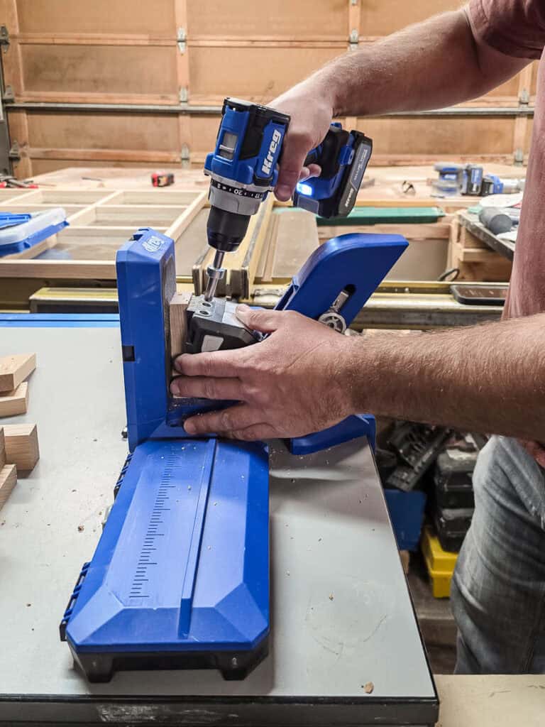 A man drilling pocket holes to build the X pieces.