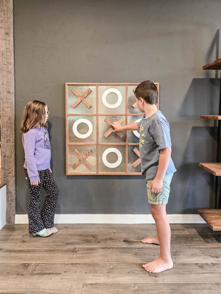 A joyful moment of two kids playing on their new DIY Tic Tac Toe board on the wall.