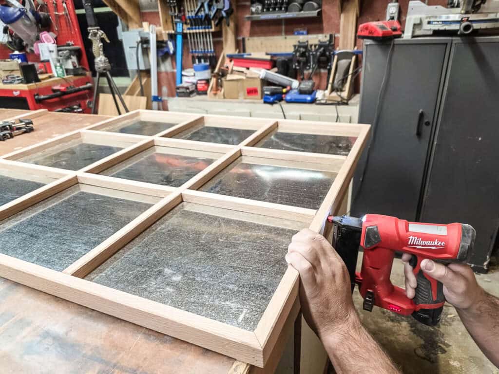 A man assembling the grid pieces for the DIY Tic Tac Toe board.