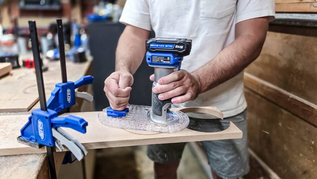 Using a trim router to cut circular holes in wood for a DIY wooden cup holder.