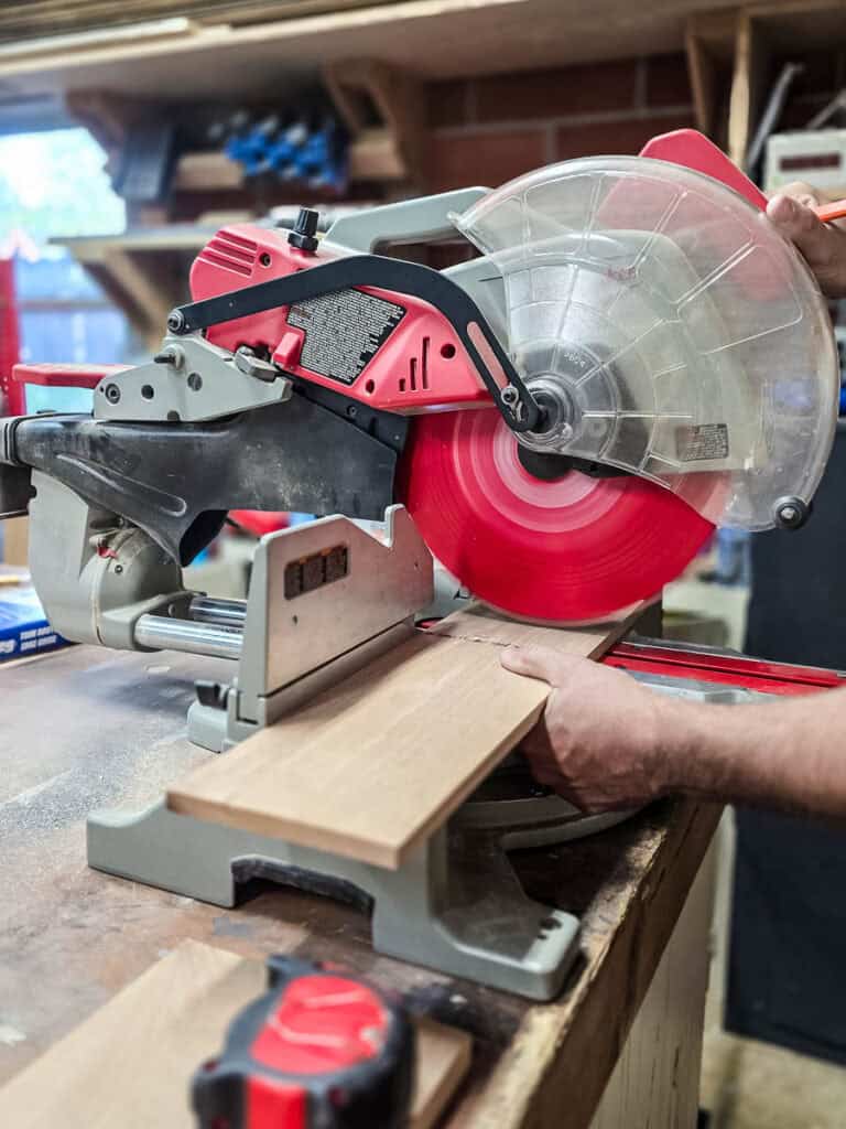 Miter saw cutting a wood board for a DIY wooden cup and napkin holder project.