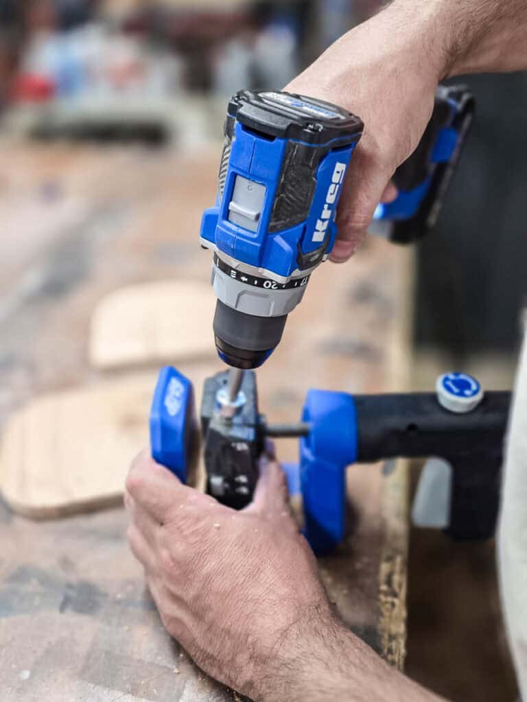 Using a cordless drill to assemble a DIY wooden cup and napkin holder with clamps.