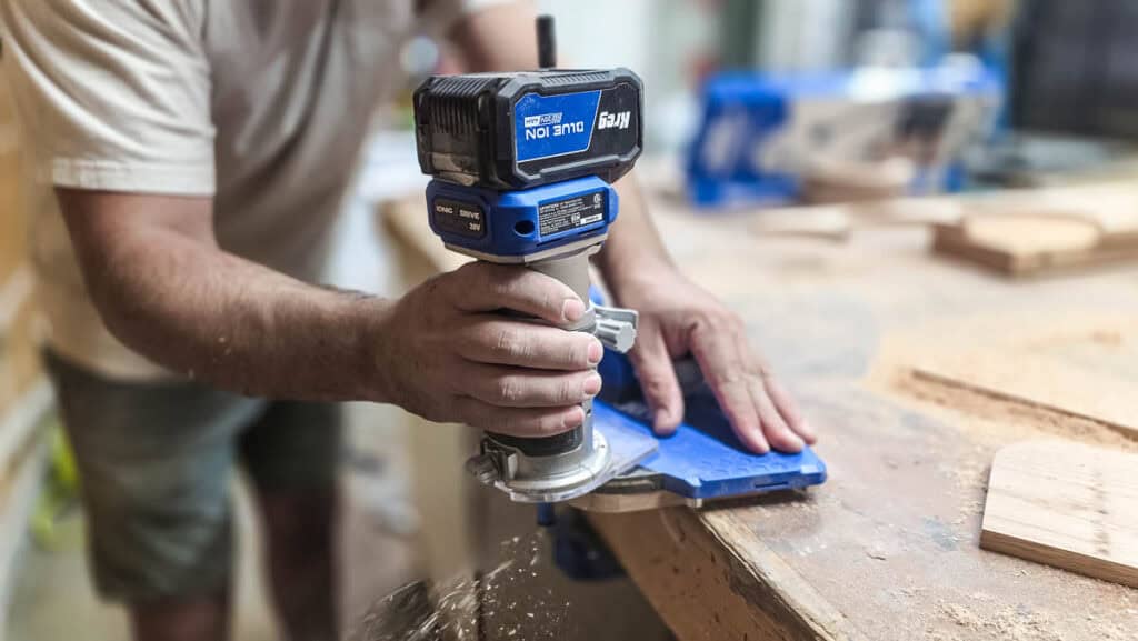 Using a trim router to round the corners of a wooden napkin holder for a DIY woodworking project.