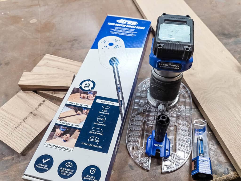 Kreg trim router circle guide kit with a compact trim router, router bit, and wooden boards laid out on a workbench, used for building DIY wooden holders for disposable cups and napkins.